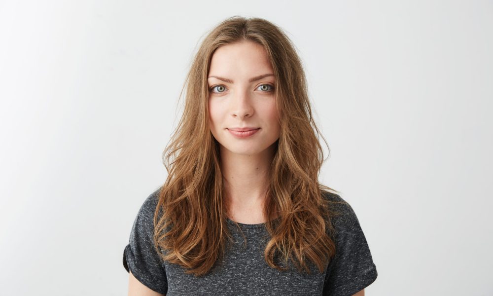 Portrait of young pretty cheerful girl smiling looking at camera over white background. Copy space.